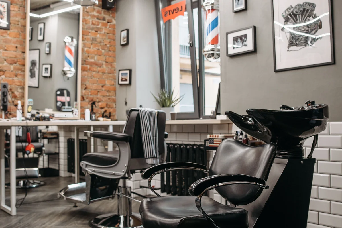 Empty barber shop interior with leather chair, mirrors, and grooming tools under warm lighting