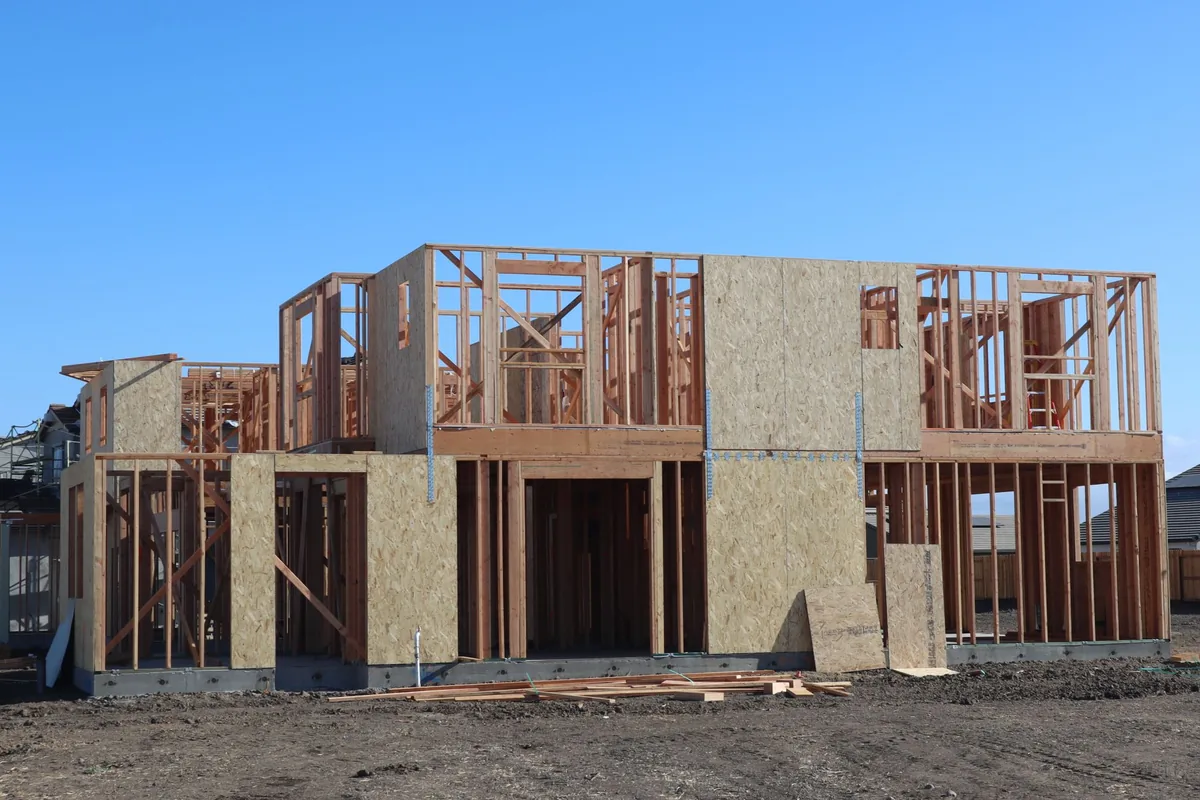 Wooden wall framing and roof trusses on a new home under construction in daylight